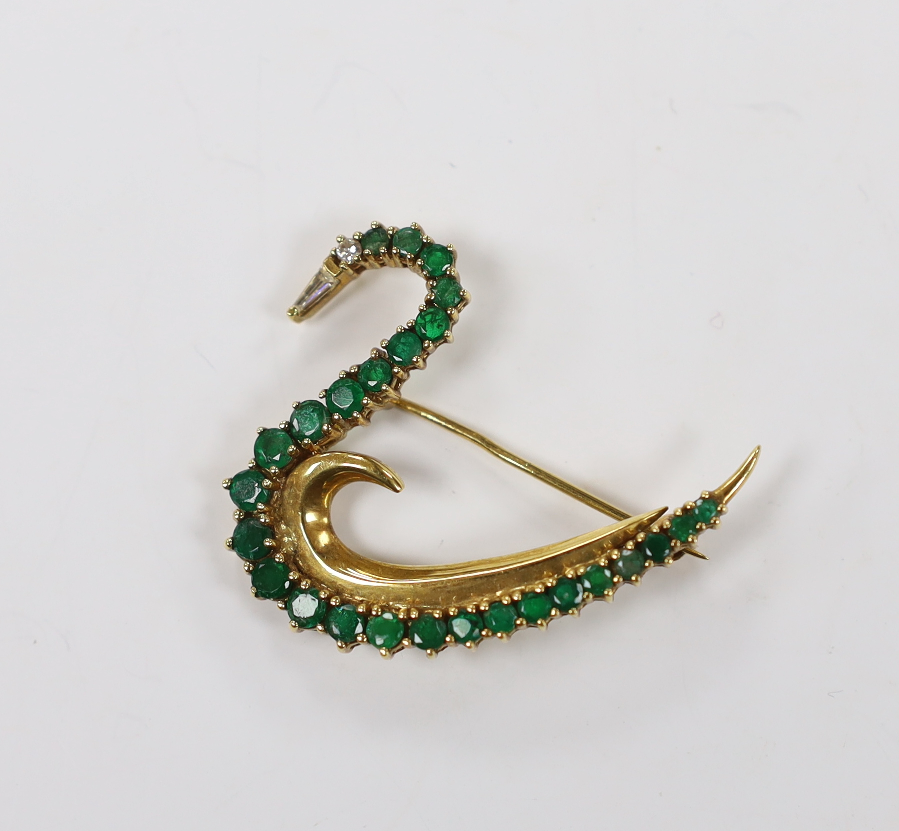 A late 1980's 18ct gold, emerald, and diamond cluster set brooch, modelled as a swan, with trapeze cut diamond set beak, maker's mark COLJ, height 34mm, width 41mm, gross weight 9.3 grams.